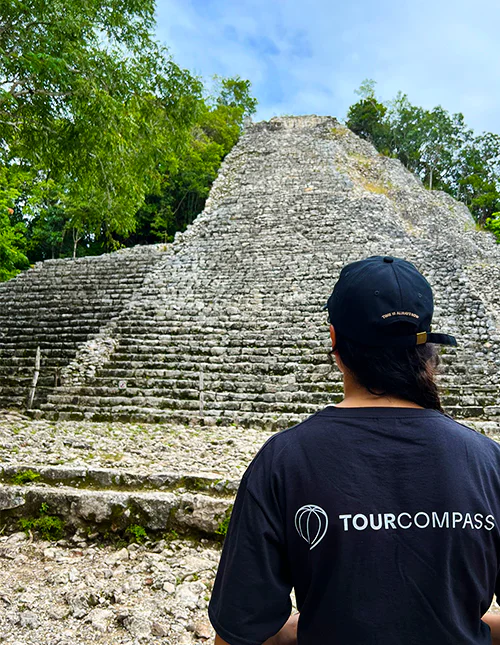 Eine Person mit einem TourCompass-T-Shirt steht vor einer Maya-Ruine in Mexiko