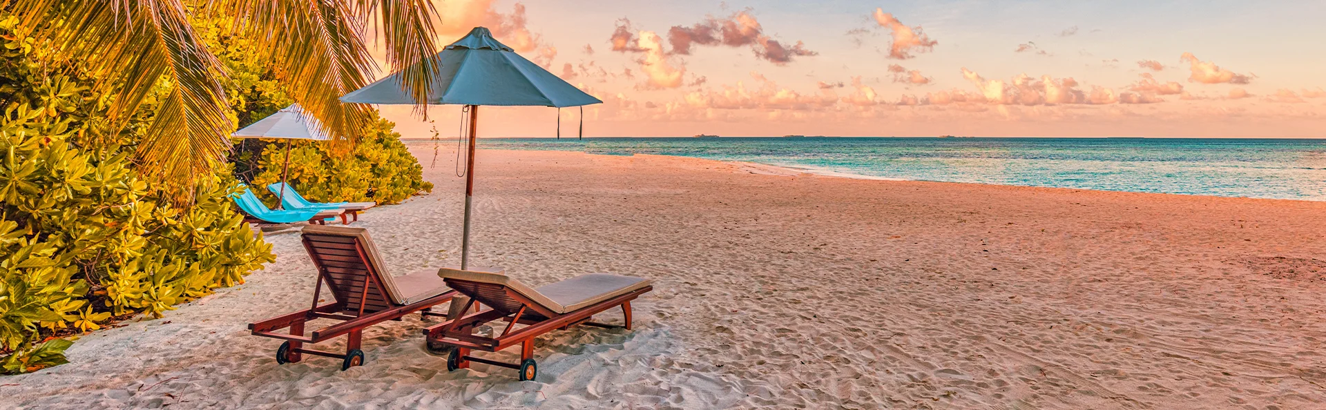 Sonnenliegen an einem tropischen Strand auf Mauritius bei Sonnenuntergang