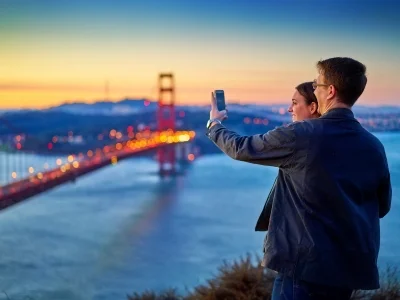Mann und Frau fotografieren die Golden Gate Bridge bei Sonnenuntergang