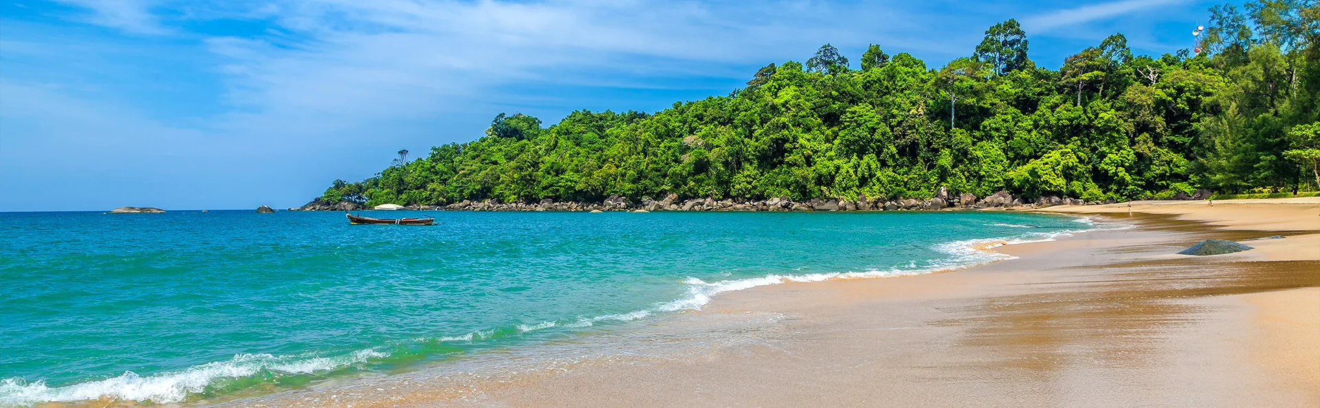 Tropischer Strand in Thailand mit türkisfarbenem Meer, weichem Sand und grünem Dschungel im Hintergrund.